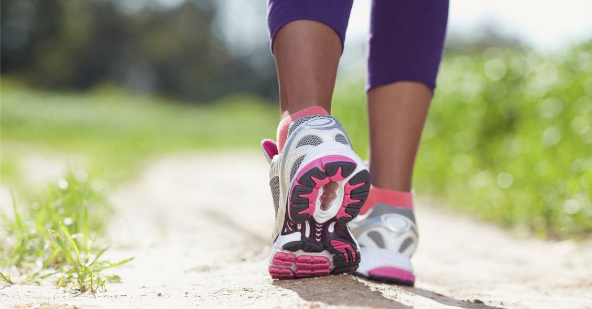 Closeup of running shoes on an African American female's feet outside on a walking trail.