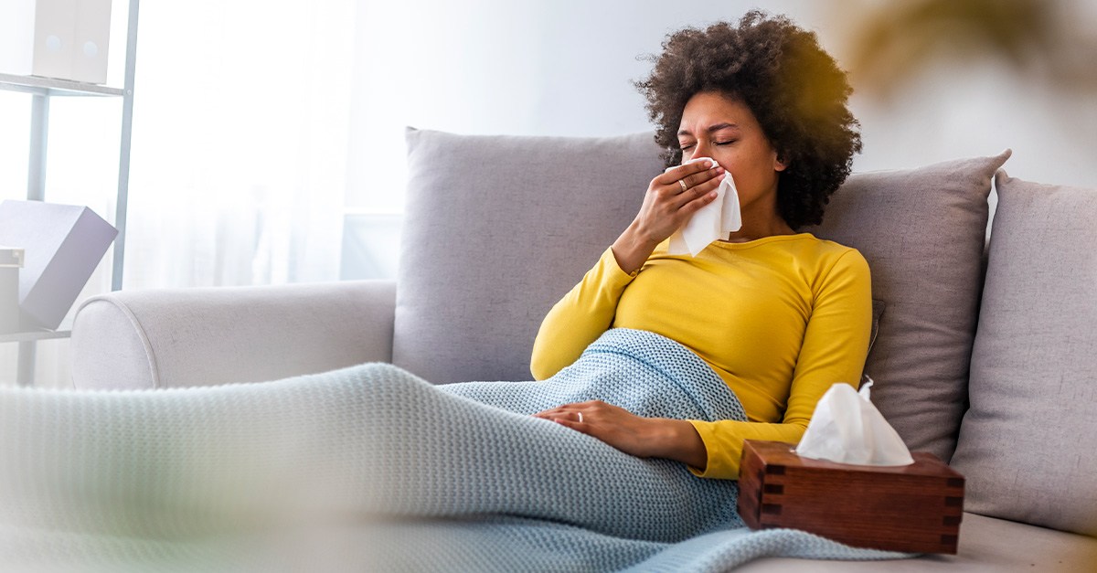 Young lady suffering from allergies at home on the couch.