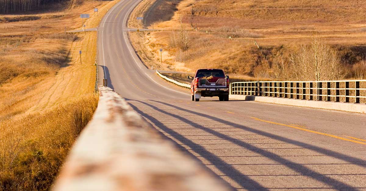 Rural country view of a road and a truck driving down it