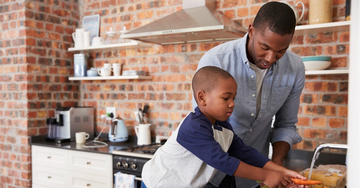 Son helping father prepare vegetables for meal